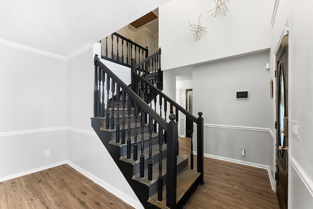 stairs featuring baseboards, wood finished floors, and crown molding