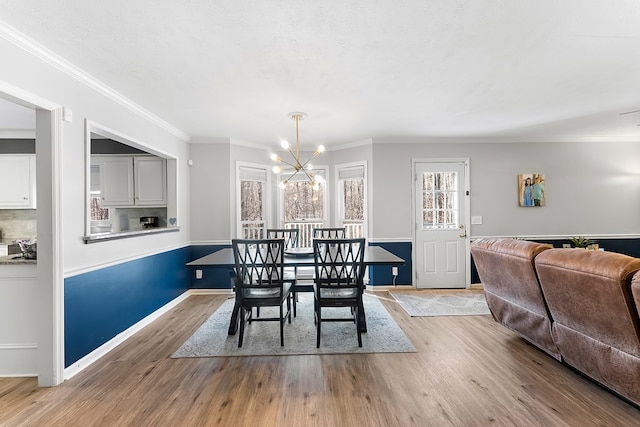 dining space featuring ornamental molding, wood finished floors, and a notable chandelier