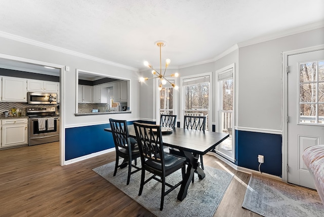 dining space featuring a textured ceiling, a notable chandelier, baseboards, dark wood finished floors, and crown molding