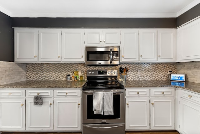 kitchen with decorative backsplash, appliances with stainless steel finishes, ornamental molding, dark stone countertops, and white cabinetry