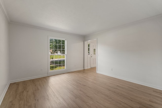 spare room featuring crown molding, wood finished floors, and baseboards