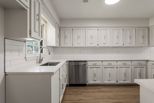 kitchen featuring dishwasher, a sink, light countertops, and white cabinetry