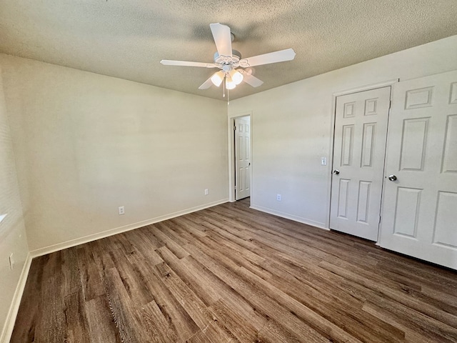 unfurnished bedroom with a ceiling fan, a textured ceiling, dark wood-style floors, and baseboards