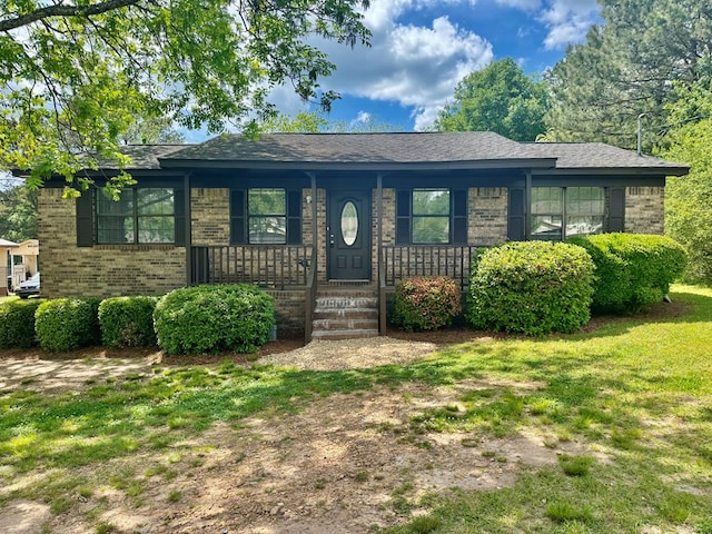 view of front of house featuring brick siding, covered porch, and a front yard