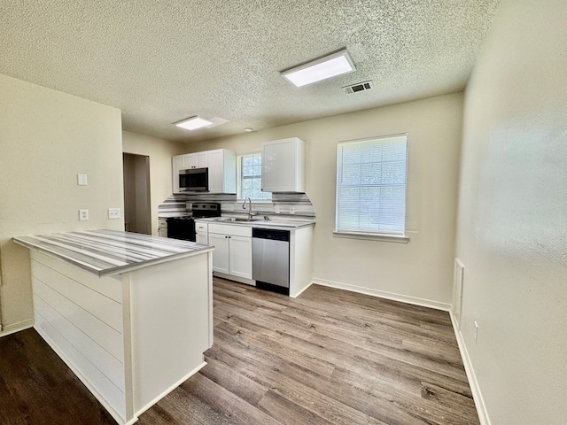 kitchen featuring a sink, white cabinetry, wood finished floors, and stainless steel appliances