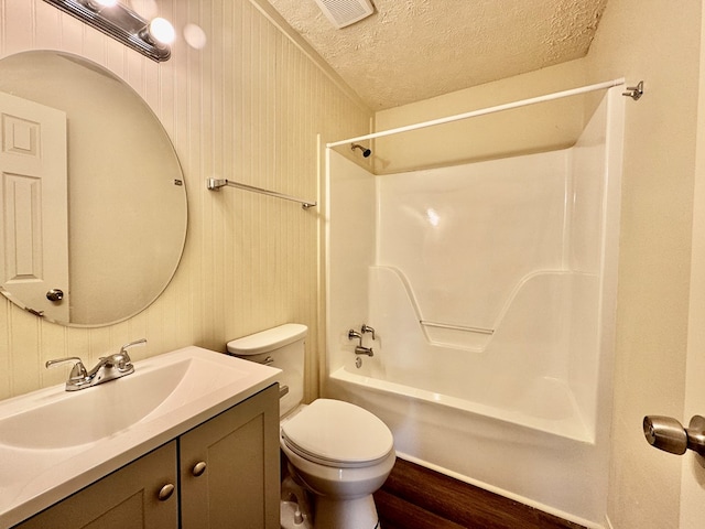 bathroom with a textured ceiling, visible vents, shower / tub combination, vanity, and toilet