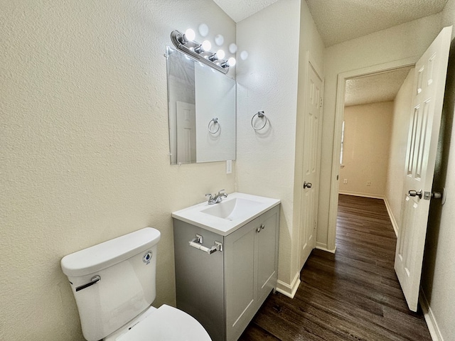 bathroom featuring vanity, baseboards, toilet, and wood finished floors
