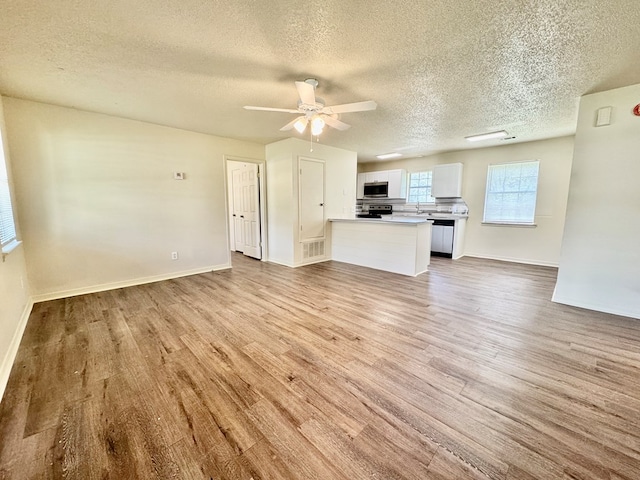 unfurnished living room with a textured ceiling and light wood-style floors