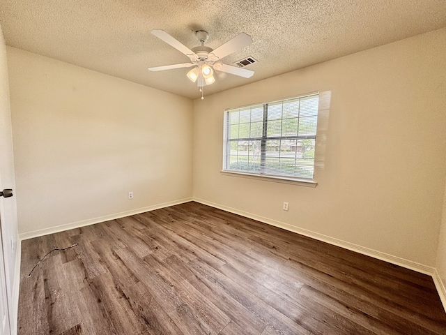 empty room with ceiling fan, a textured ceiling, visible vents, baseboards, and dark wood-type flooring