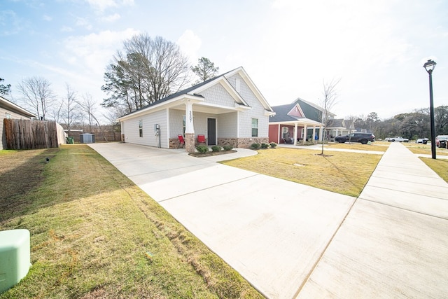 craftsman house featuring driveway, a front yard, and fence