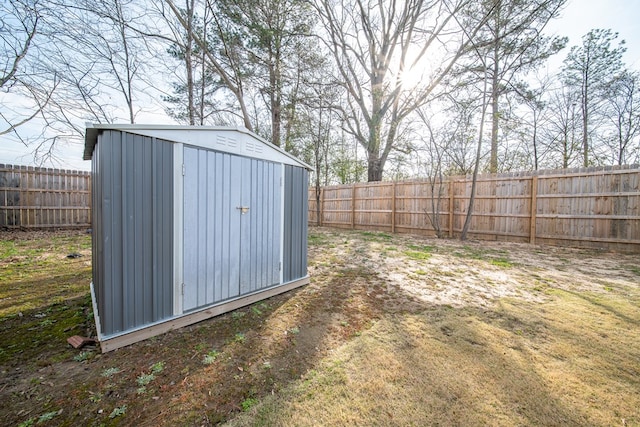 view of yard featuring an outbuilding, a fenced backyard, and a storage shed