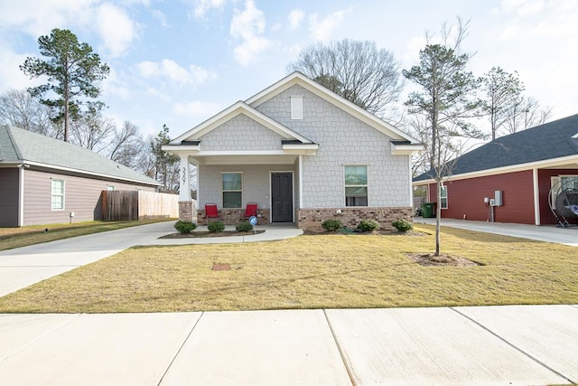 craftsman house with brick siding, a porch, concrete driveway, a front yard, and fence