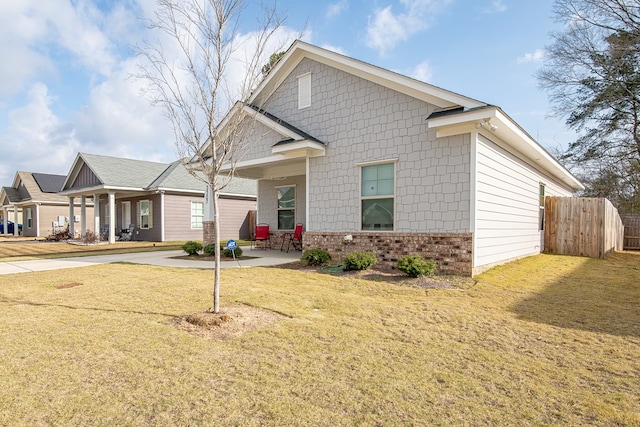 view of front of property with brick siding, a front lawn, and fence