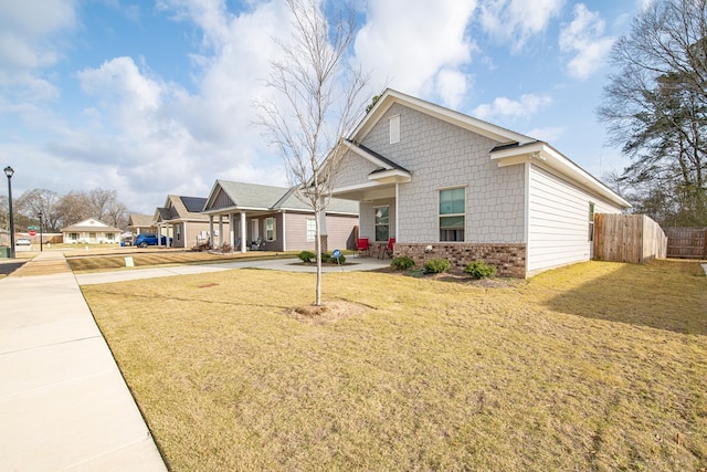 view of front of home featuring driveway, brick siding, a front lawn, and fence