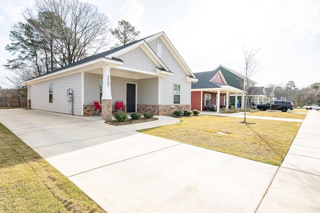 craftsman-style home with covered porch, brick siding, driveway, and a front lawn