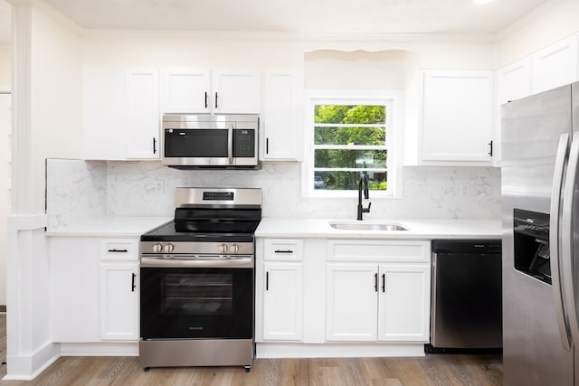 2917 Doyle Ave, Columbus, GA 31907 - kitchen featuring stainless steel appliances, a sink, white cabinets, light countertops, and light wood-style flooring
