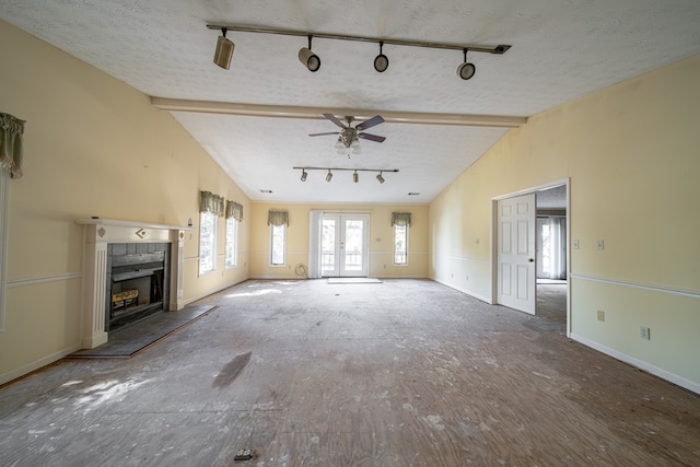 unfurnished living room with a tile fireplace, ceiling fan, french doors, vaulted ceiling, and a textured ceiling