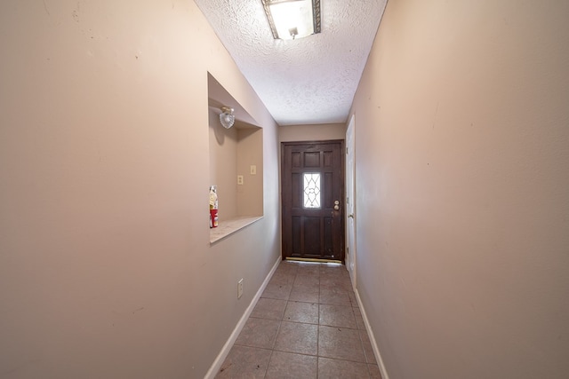 doorway to outside with tile patterned floors and a textured ceiling