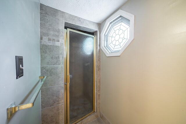 bathroom featuring an enclosed shower and a textured ceiling