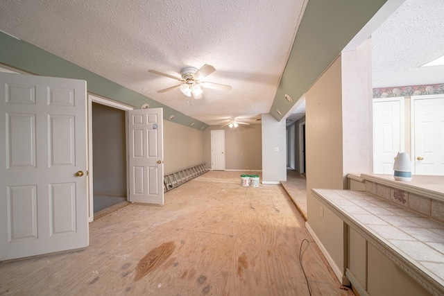 interior space featuring ceiling fan, a textured ceiling, and light hardwood / wood-style flooring