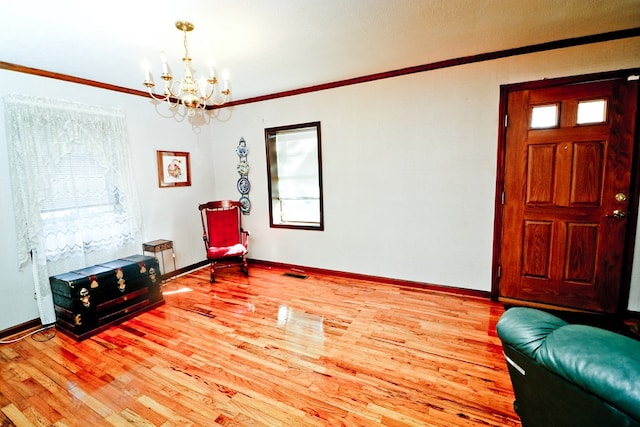 entryway with ornamental molding, light hardwood / wood-style floors, and a chandelier