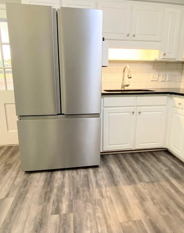 kitchen featuring dark countertops, wood finished floors, freestanding refrigerator, and a sink