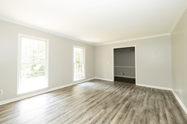 unfurnished room featuring visible vents, wood finished floors, baseboards, and ornamental molding