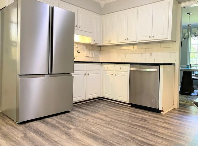 kitchen with light wood-style flooring, tasteful backsplash, dark countertops, stainless steel appliances, and white cabinets