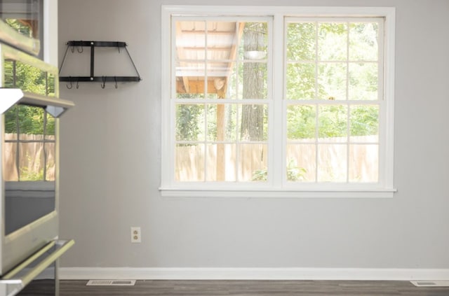 unfurnished dining area featuring wood finished floors, plenty of natural light, baseboards, and visible vents