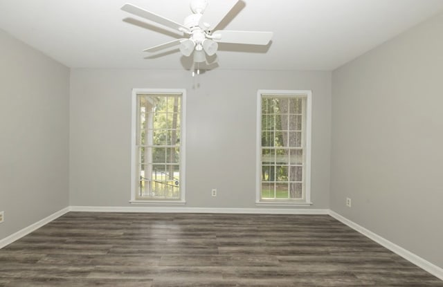 empty room with baseboards, dark wood finished floors, and a ceiling fan