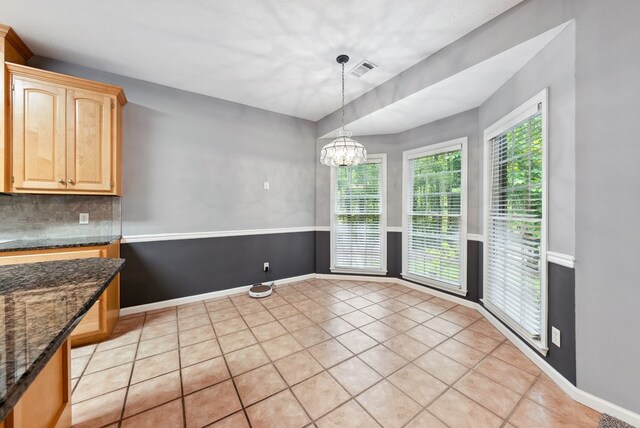 unfurnished dining area featuring light tile patterned flooring, a chandelier, and baseboards