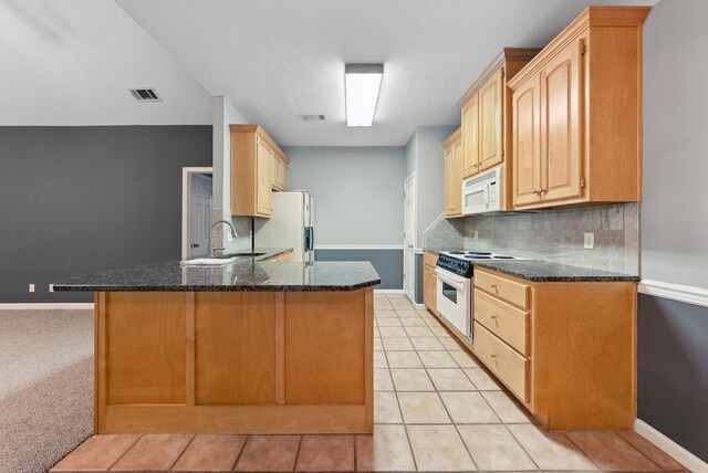 kitchen featuring white appliances, a sink, backsplash, a peninsula, and baseboards