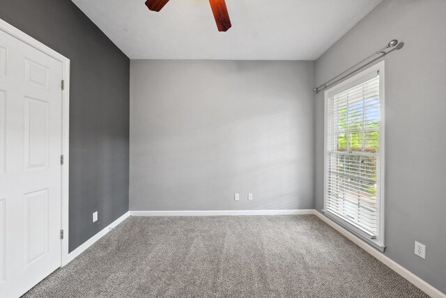 carpeted empty room with ceiling fan and baseboards