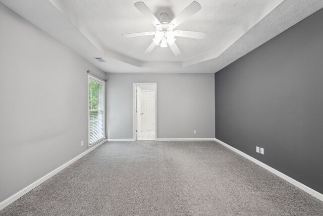unfurnished room with a raised ceiling, a ceiling fan, baseboards, carpet, and a textured ceiling