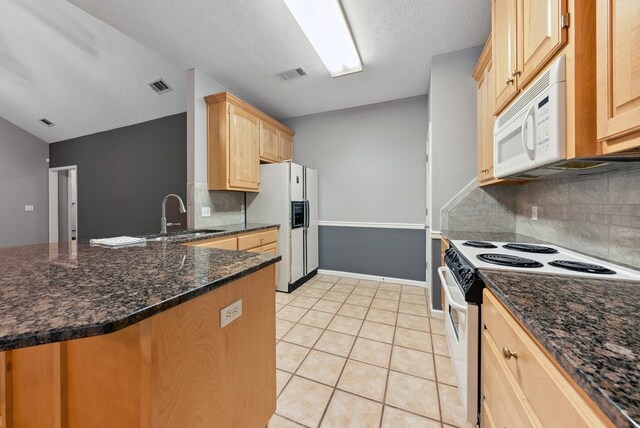 kitchen featuring white appliances, a sink, light brown cabinets, decorative backsplash, and a peninsula