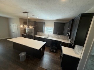 7300 Pine Chase Dr, Midland, GA 31820 - kitchen featuring light countertops, a kitchen island, dark wood-style floors, pendant lighting, and a textured ceiling