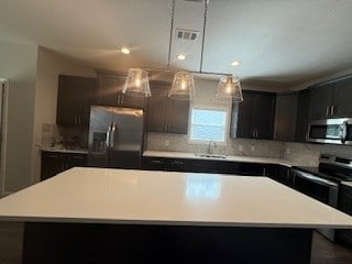 7300 Pine Chase Dr, Midland, GA 31820 - kitchen featuring appliances with stainless steel finishes, tasteful backsplash, light countertops, and a kitchen island