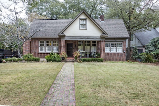 english style home with covered porch and a front lawn