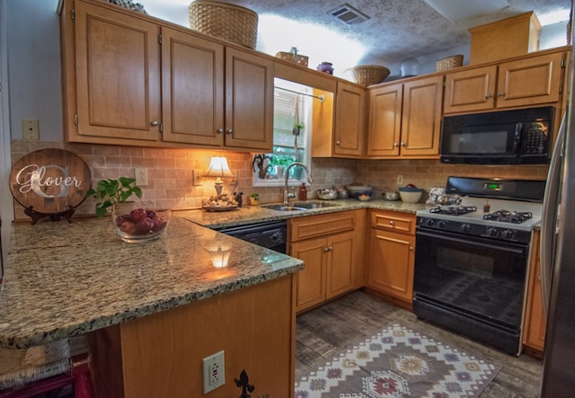 5063 3rd Ave, Columbus, GA 31904 - kitchen with black appliances, a peninsula, light stone countertops, backsplash, and wood finished floors