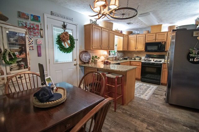 5063 3rd Ave, Columbus, GA 31904 - kitchen featuring black microwave, freestanding refrigerator, gas range oven, a peninsula, and a chandelier