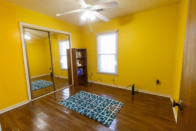 interior space with a ceiling fan, a closet, baseboards, and wood finished floors