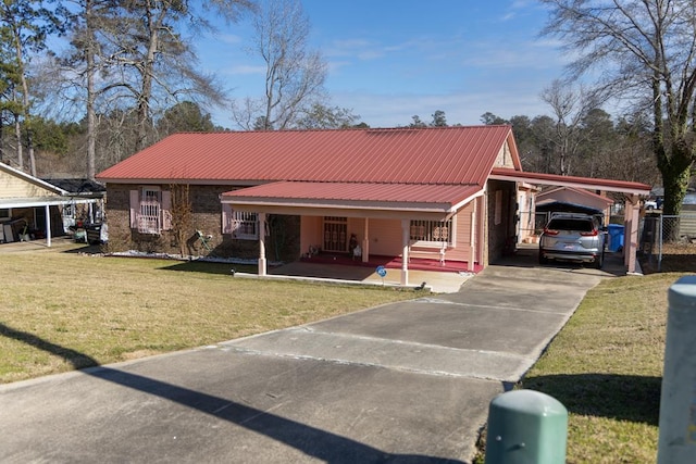 view of front facade featuring brick siding, a front yard, metal roof, an attached carport, and driveway