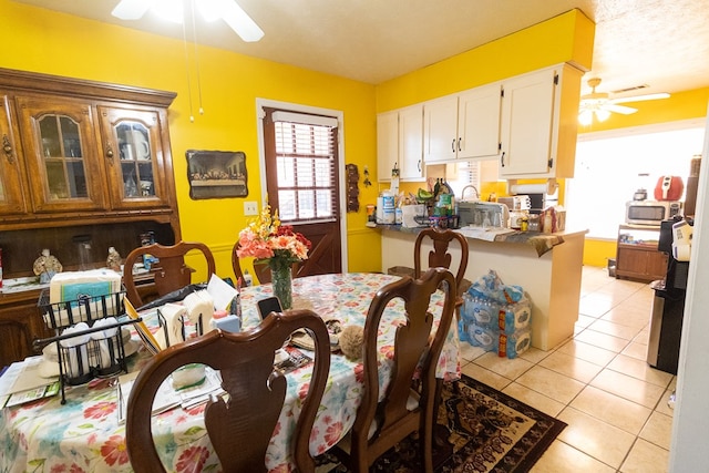 dining space featuring ceiling fan, a textured ceiling, and light tile patterned flooring