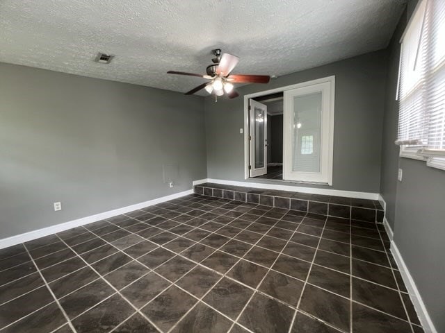 4154 Will Rhoades Dr, Columbus, GA 31909 - spare room with ceiling fan, a textured ceiling, dark tile patterned flooring, and baseboards