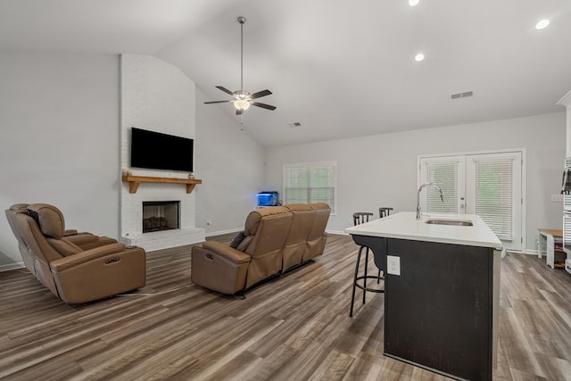 living room with hardwood / wood-style flooring, a fireplace, ceiling fan, and sink