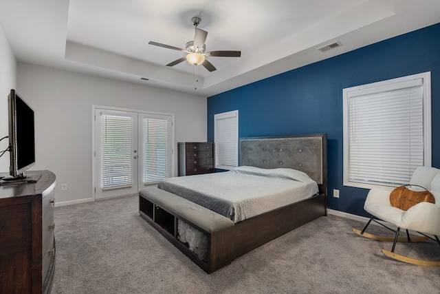 bedroom featuring ceiling fan, a raised ceiling, and light carpet