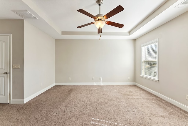 carpeted empty room with a raised ceiling and ceiling fan