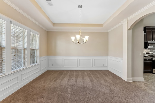 carpeted spare room featuring an inviting chandelier and a raised ceiling