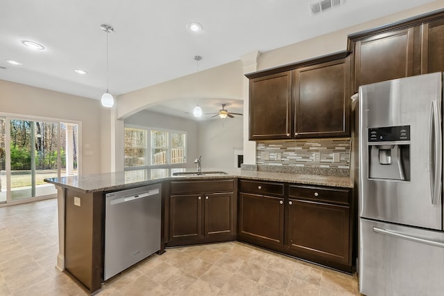 kitchen with appliances with stainless steel finishes, decorative light fixtures, light stone countertops, and sink