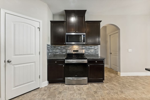 kitchen featuring dark stone countertops, dark brown cabinets, stainless steel appliances, and tasteful backsplash